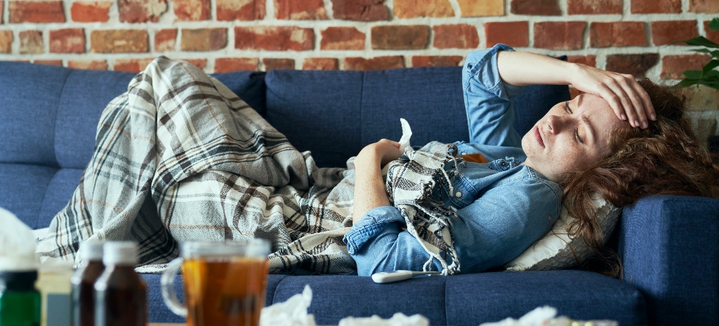 Young woman lying on sofa and having a headache, experiencing withdrawal symptoms from substance use.