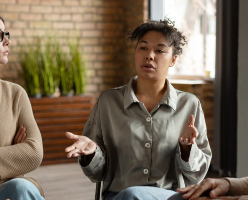 A woman sitting in a group and talking for the topic best inpatient rehab california.