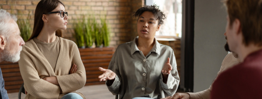 A woman sitting in a group and talking for the topic best inpatient rehab california.