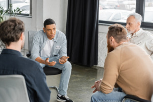 A group of men talking in a group therapy session for the topic best rehab centers for men.