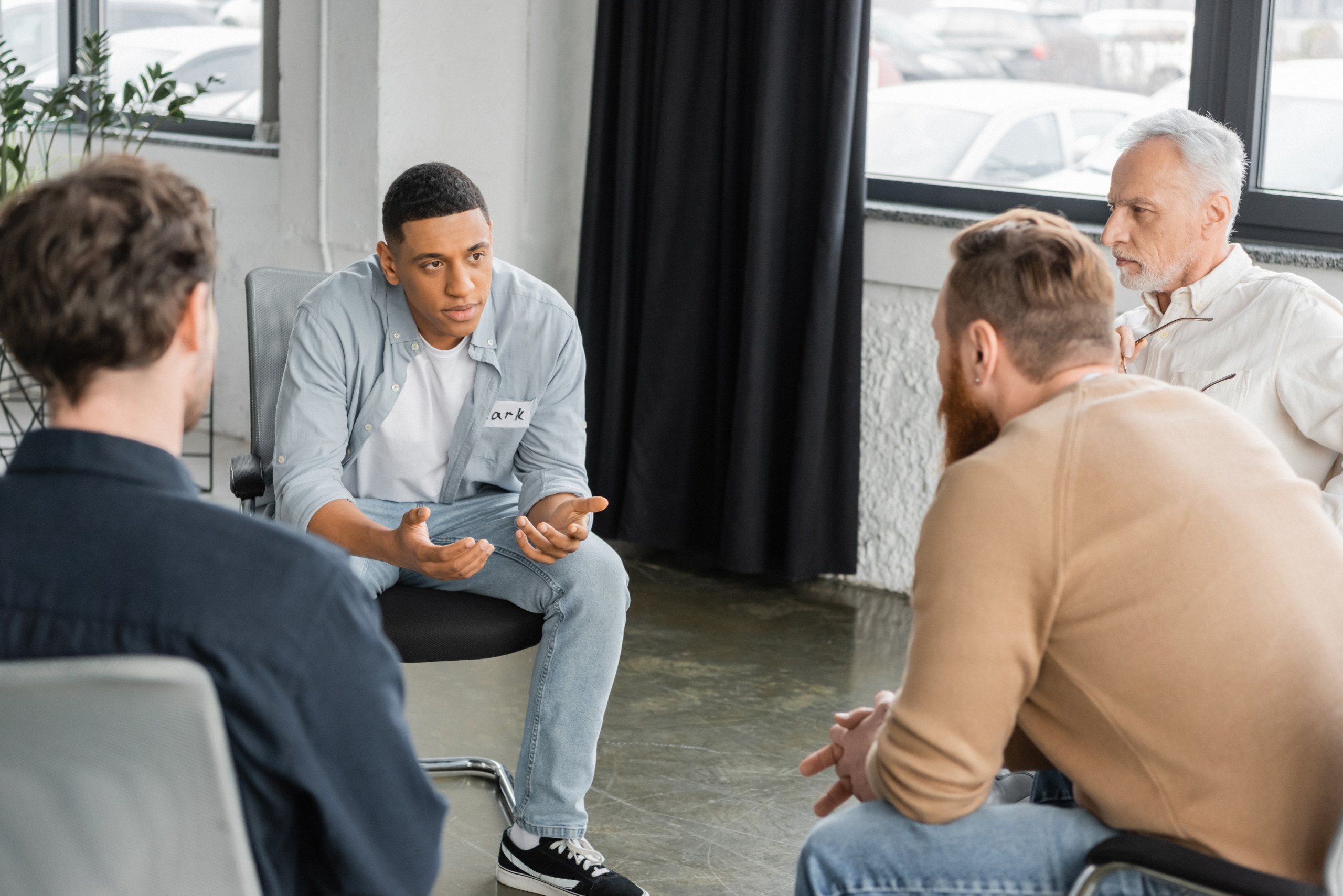 A group of men talking in a group therapy session for the topic best rehab centers for men.